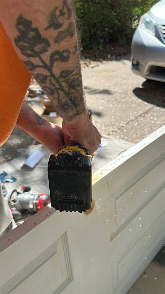 Technician sanding a white panel door smooth before refinishing — door repair service in Denver