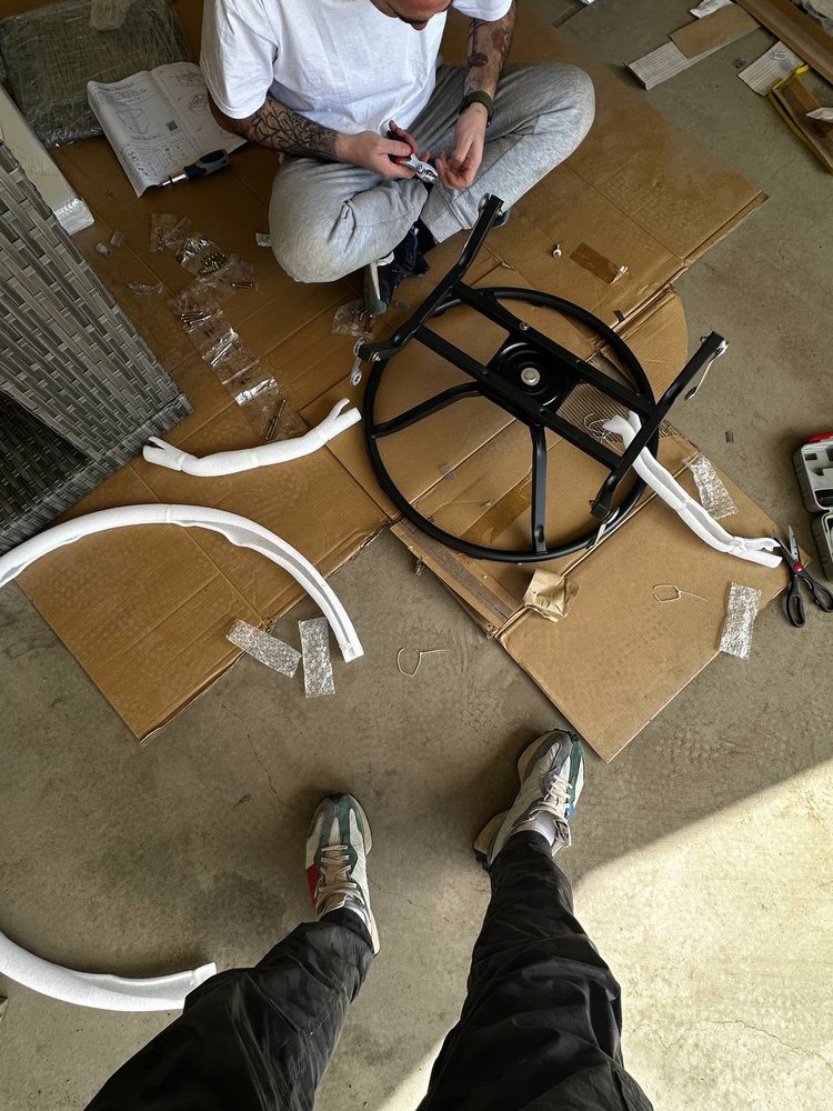 Flat-pack furniture frame being assembled on protective floor board — furniture assembly service in Denver
