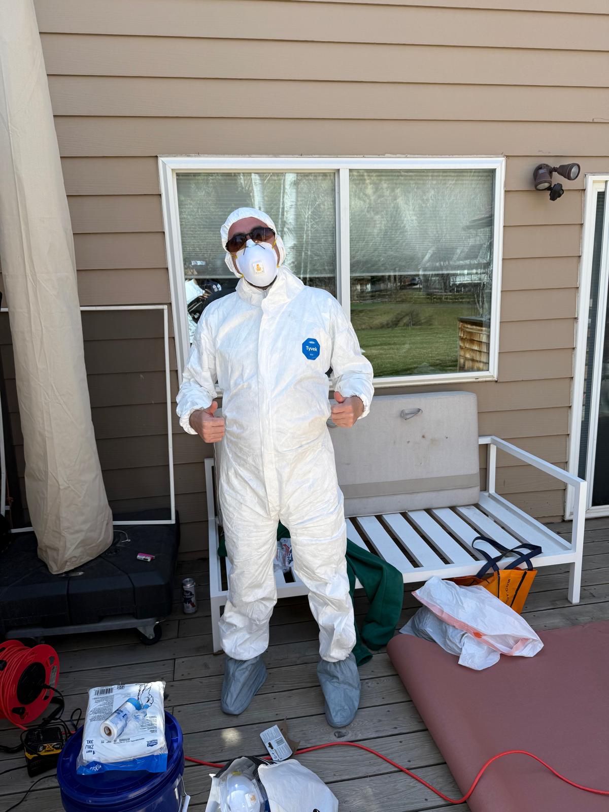 Technician in full protective coveralls and respirator before a spray job — exterior painting service in Denver