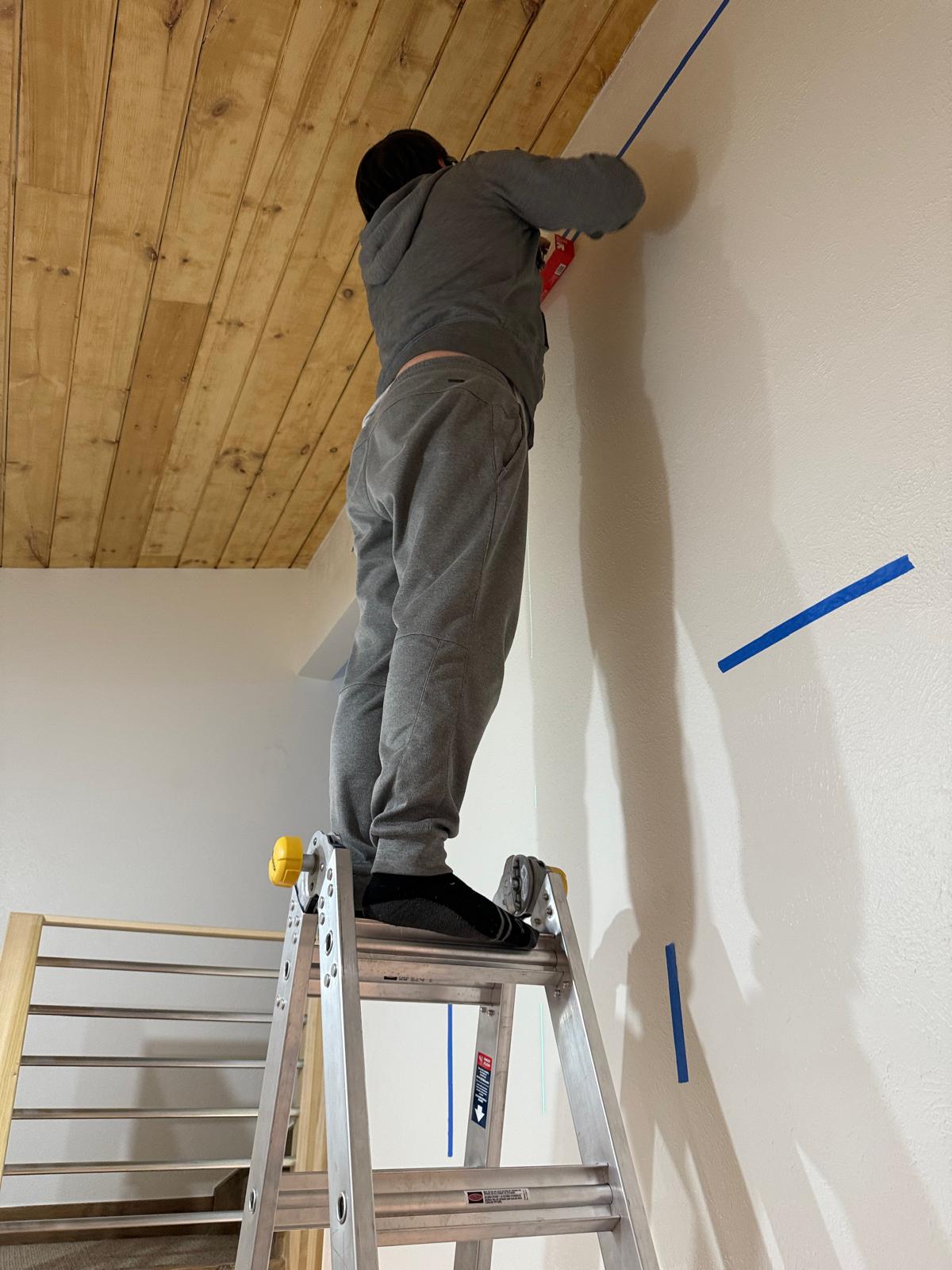 Painter cutting a clean line where a wall meets a tongue-and-groove ceiling — interior painting service in Denver