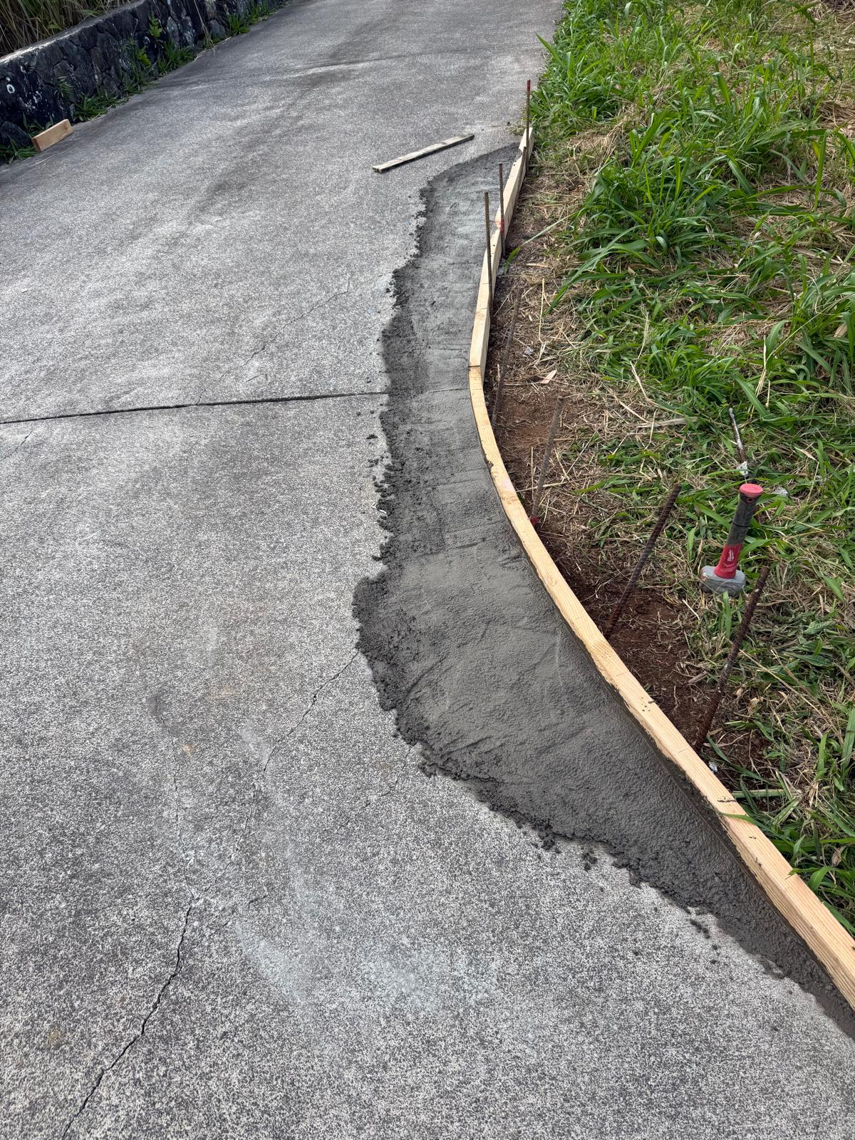 New concrete curb poured along a sloping driveway edge — exterior repair service in Denver