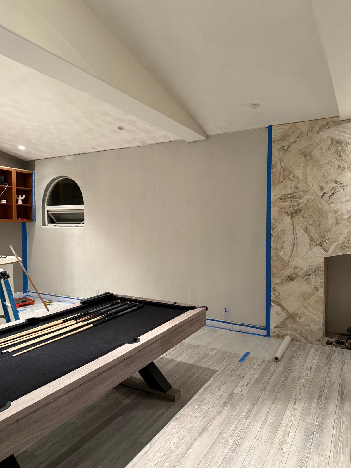 Game room wall masked with blue tape and floor protection before an interior repaint — painting in Denver