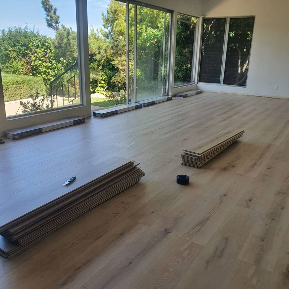 Wide living space with newly laid wood-look plank flooring running to the windows — flooring installation service in Denver