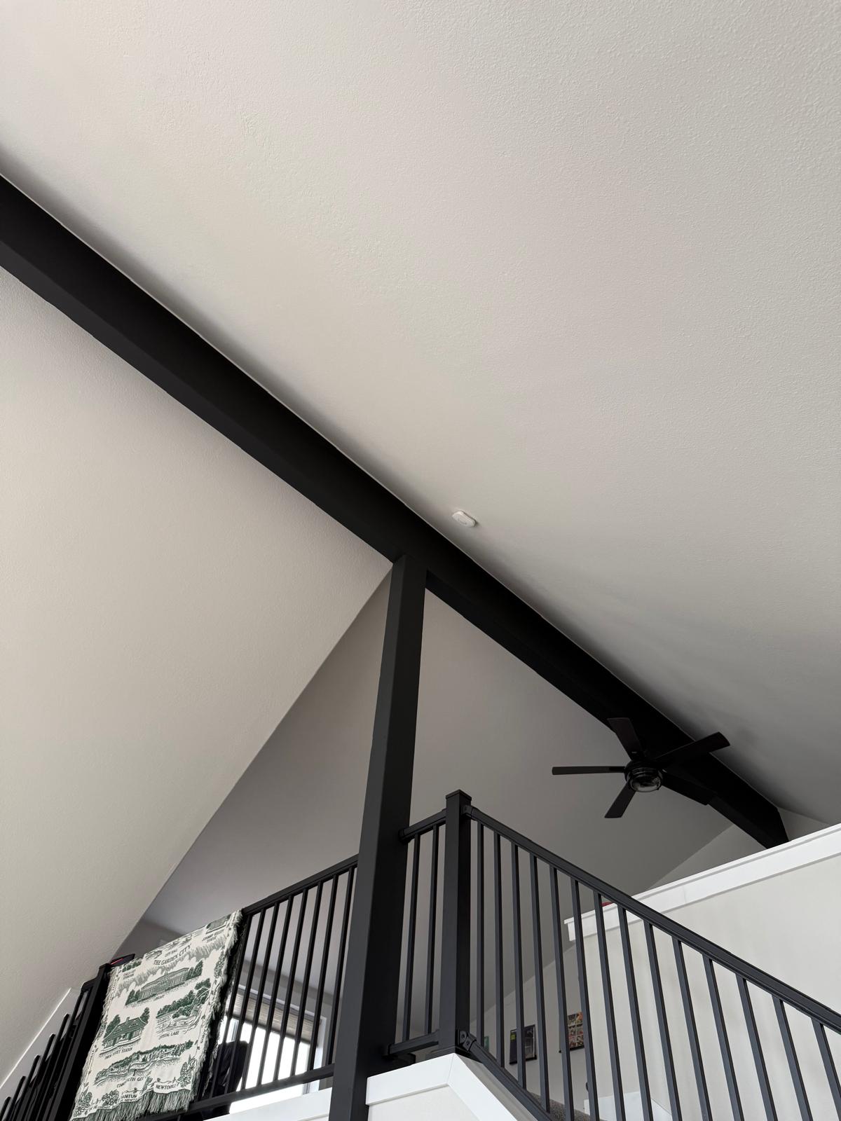 Repainted vaulted stairwell with black metal railing and crisp ceiling lines — interior painting service in Denver