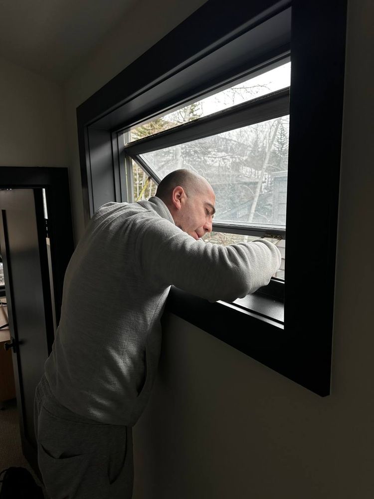 Installer fitting a black-framed window unit square into its opening — installation service in Denver