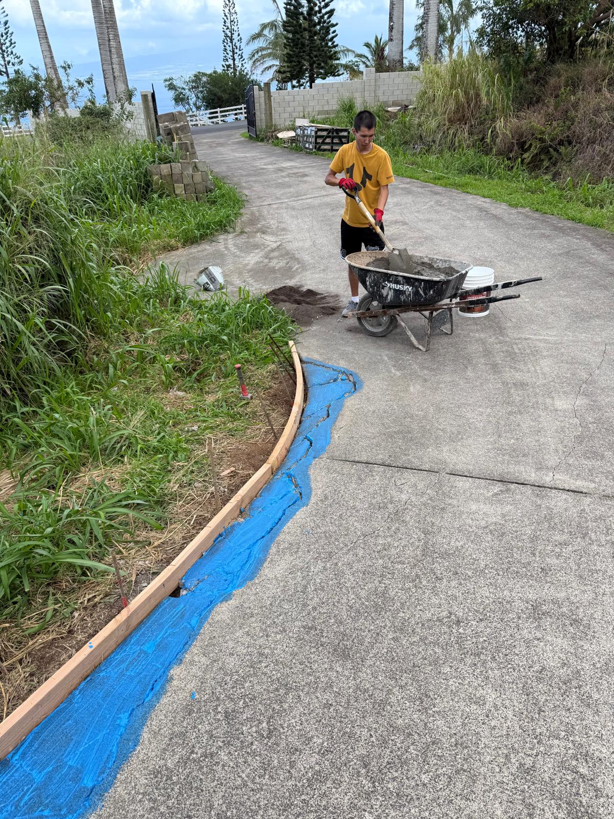 Crew member wheeling material along a driveway edged with fresh concrete — property maintenance service in Denver