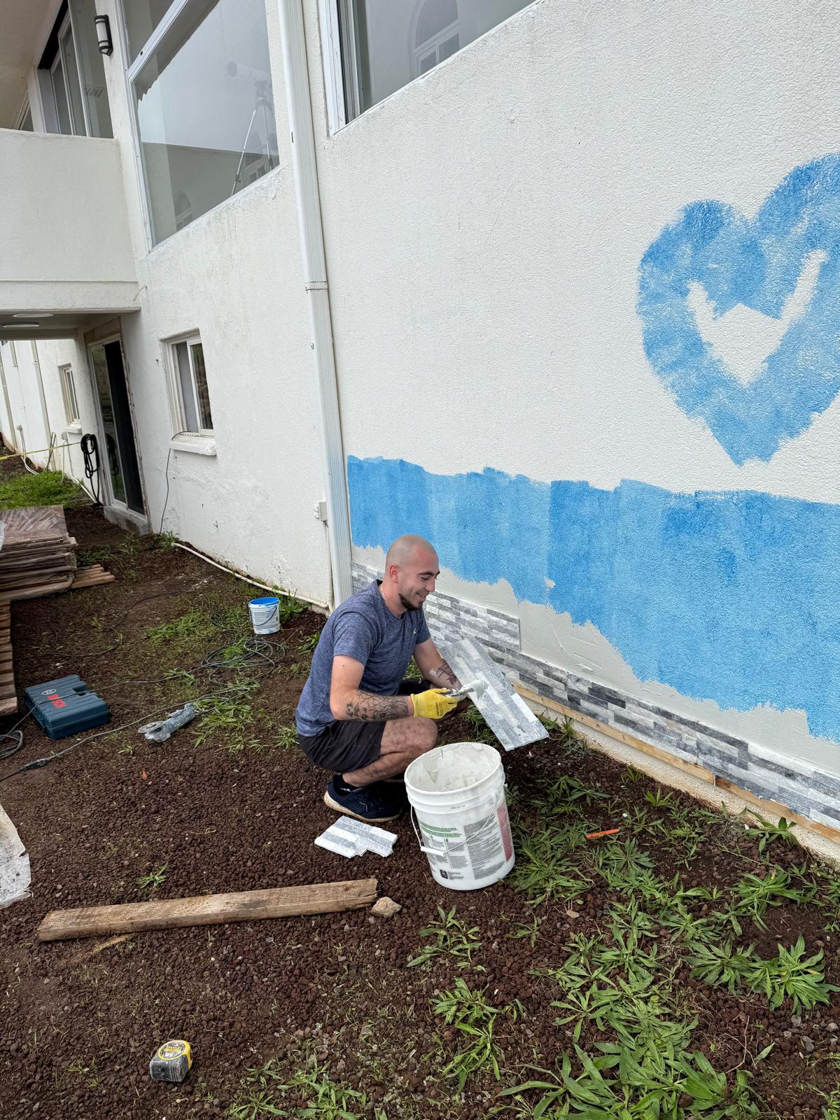 Crew member masking a stone-clad exterior wall before spraying — exterior painting service in Denver