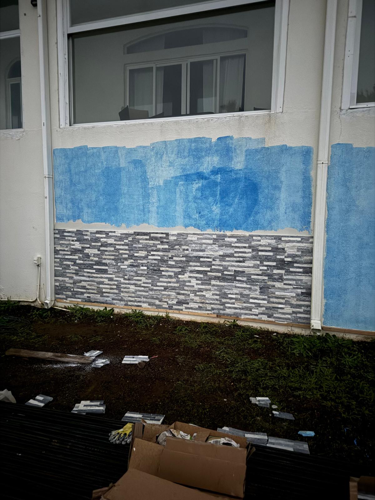 Masked exterior wall with new stacked-stone base course completed — exterior painting service in Denver