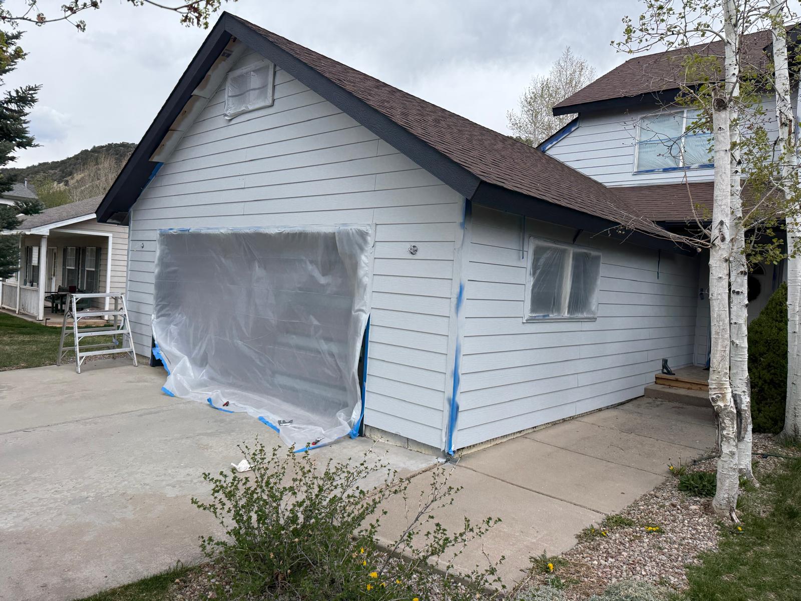 Window opening fully sheeted off while the surrounding siding is coated — exterior painting service in Denver