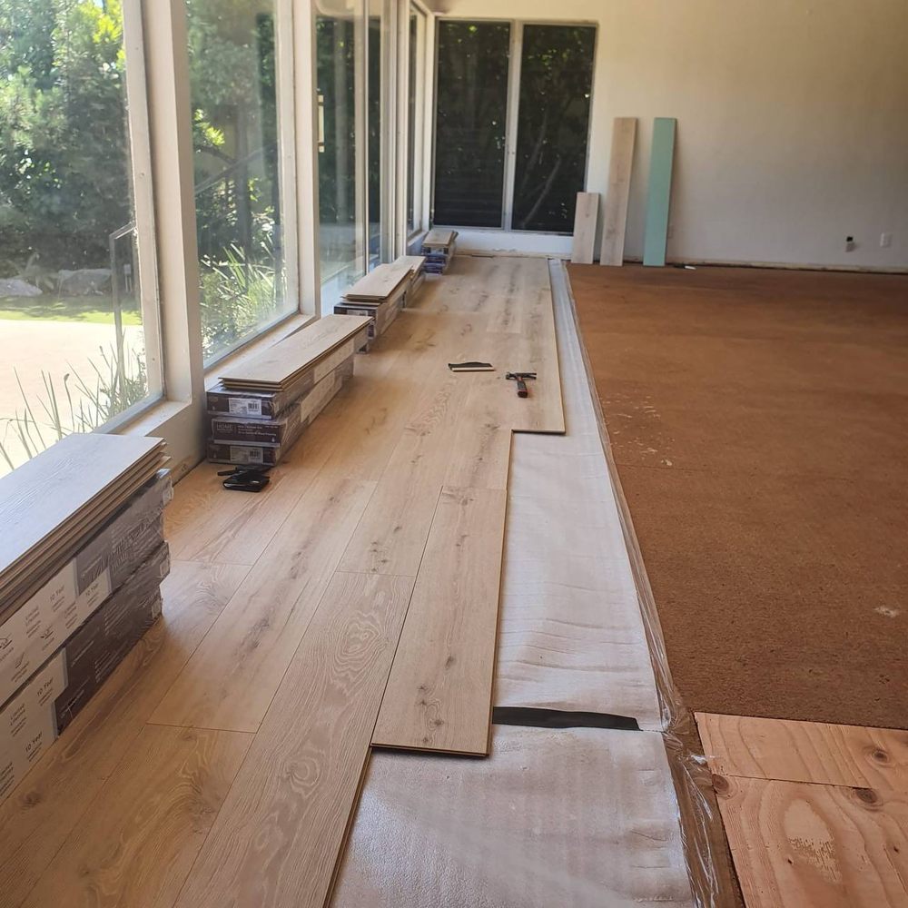 Rows of plank flooring staged along a wall of windows before fitting — flooring installation service in Denver