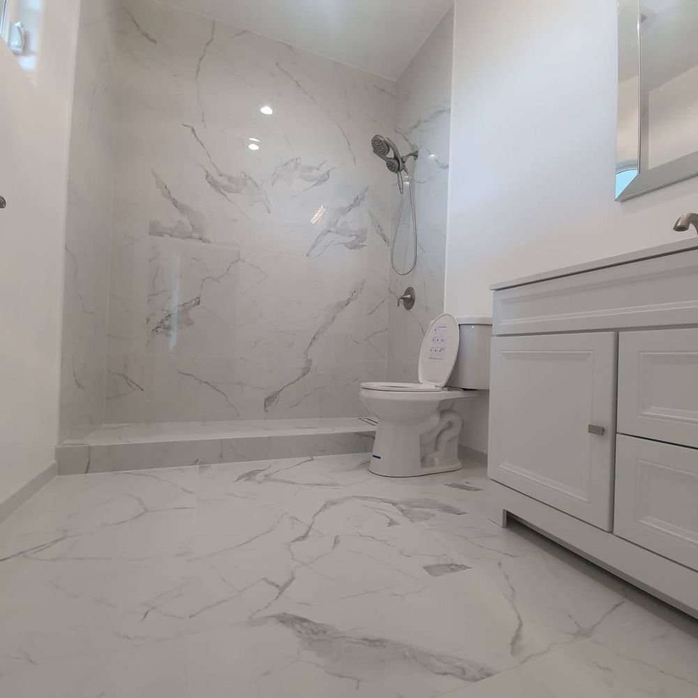 Finished bathroom with marble-look tile walls and floor after refit — bathroom repair and tiling service in Denver