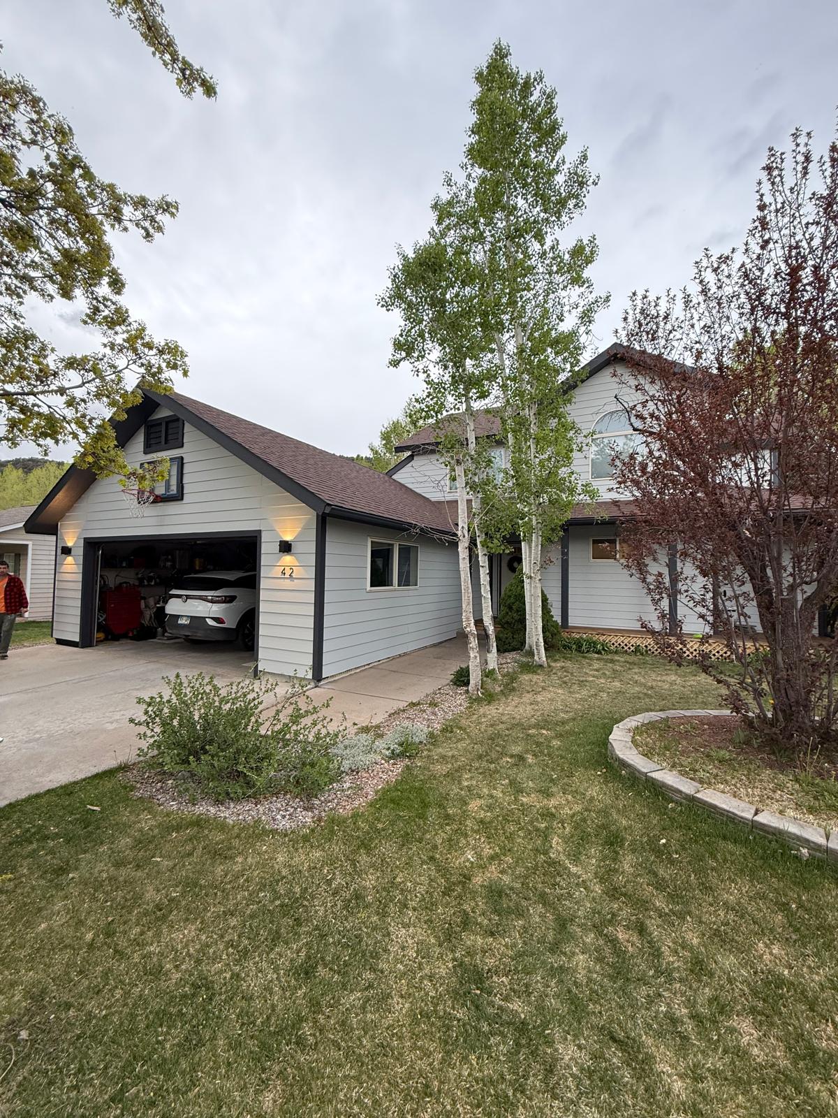 Finished home exterior with repainted garage door and trim seen from the street — exterior painting service in Denver